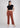 Woman wearing rusty brown trousers with black crop top