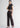 Woman in brown trousers and black top, side pose