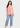 Light pink sleeveless top with blue jeans, full-length look