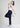 Model in navy trousers holding sunglasses, side pose